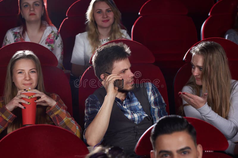 Brünettemann, der am Anruftelefon an der Kinohalle spricht stockfotos Brünettemann, der am Anruftelefon an der Kinohalle spricht stockfotos