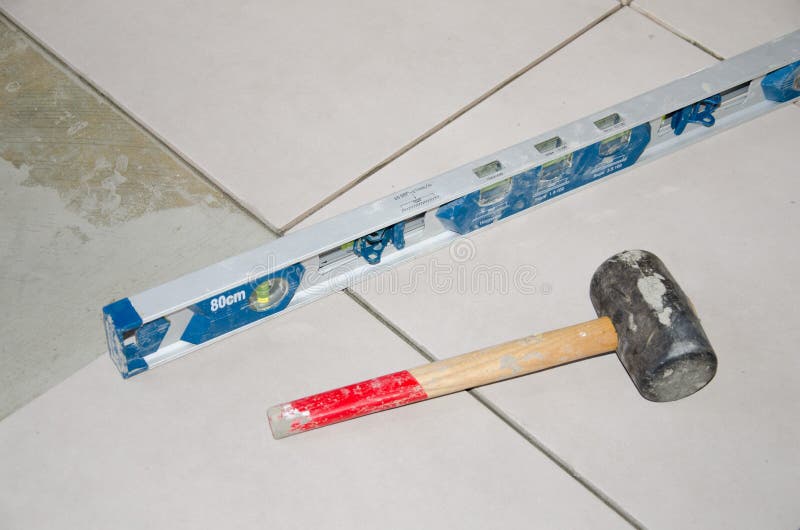 Bubble level and rubber mallet on a floor tiling stock photography Bubble level and rubber mallet on a floor tiling stock photography