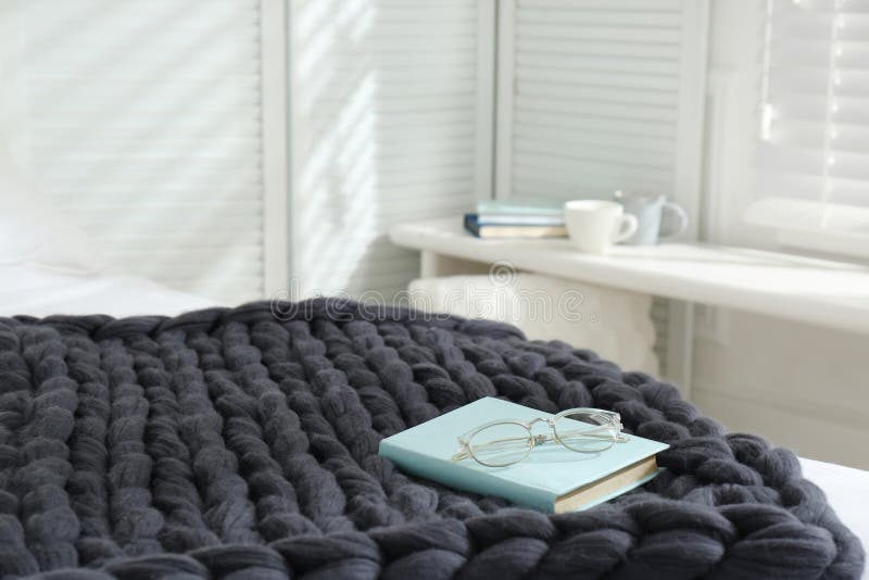Buch und Gläser auf gestricktem Merinowolleplaid im Schlafzimmerraum für Text stockfotografie