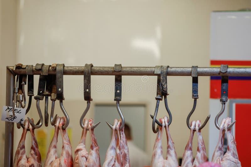 Lamb carcass hang from iron hooks for sale in a Romanian butcher shop before Easter