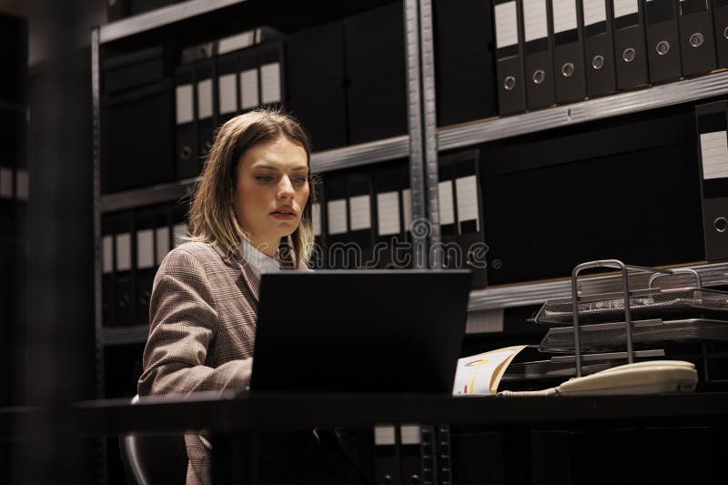 Caucasian bookkeeper reading administrative files, working late at night in corporate depository. Businesswoman in formal suit analyzing accountancy report, checking management research. Caucasian bookkeeper reading administrative files, working late at night in corporate depository. Businesswoman in formal suit analyzing accountancy report, checking management research