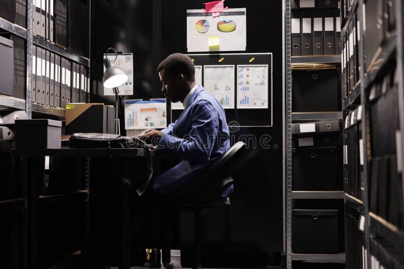 African american bookkeeper analyzing accountancy report, checking administrative files in storage room. Depository employee working in bureaucracy record, discovering management research. African american bookkeeper analyzing accountancy report, checking administrative files in storage room. Depository employee working in bureaucracy record, discovering management research