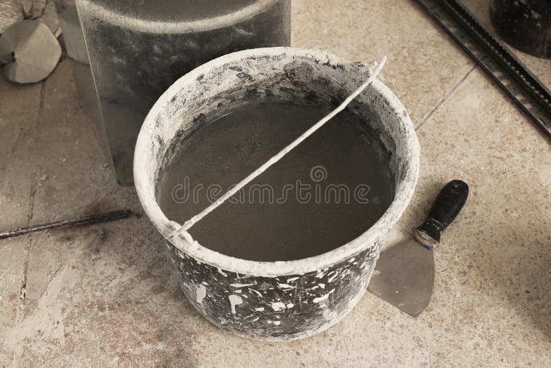 Bucket of Adhesive Mix and Spatula on Floor Indoors Tiles Installation