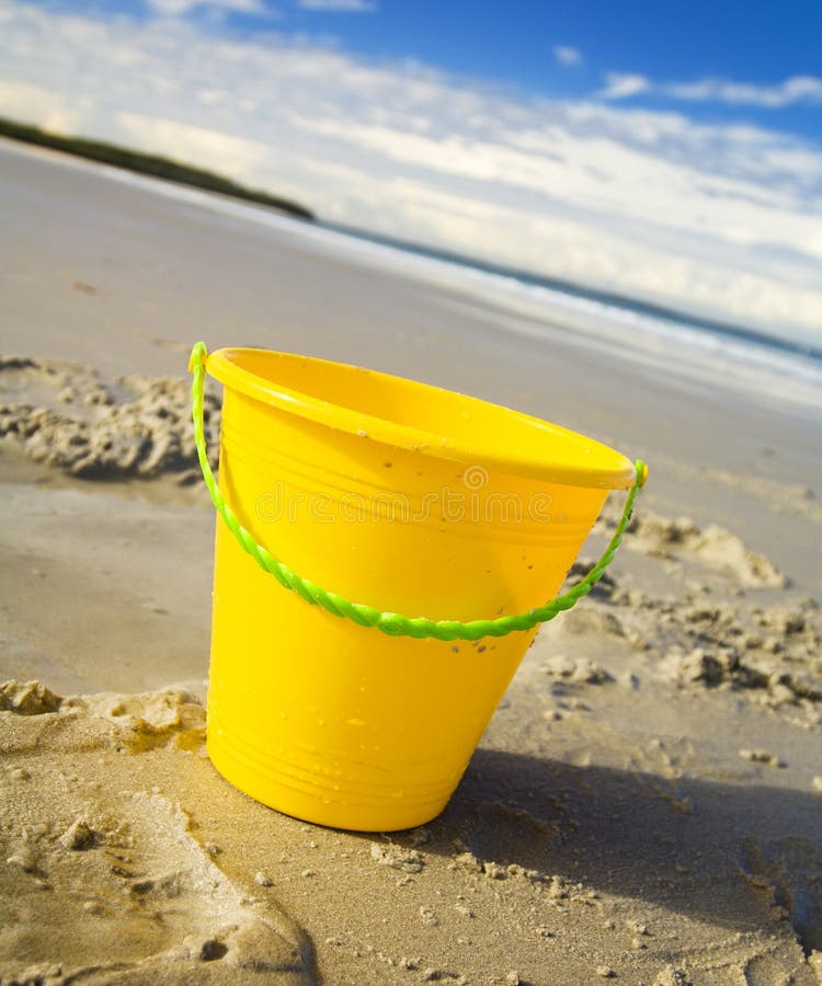 Childrens toy bucket in the sand at the beach stock images.