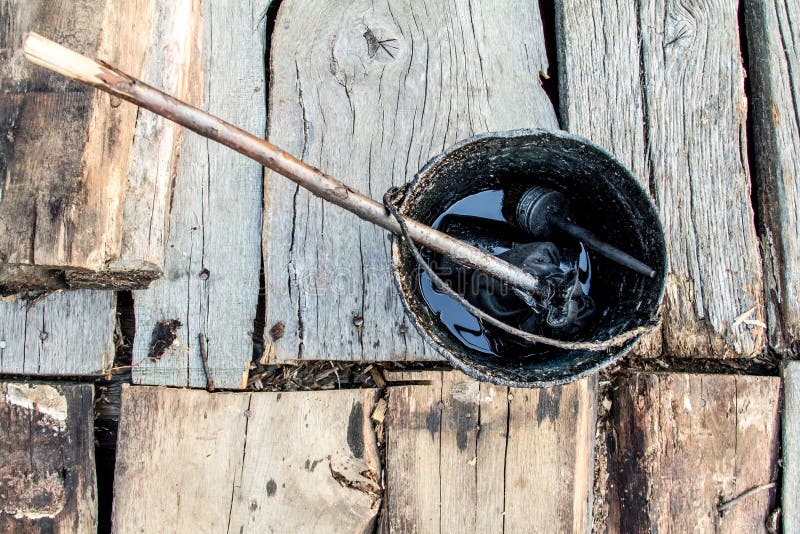 A bucket of black tar boils on the fire for use in repair and waterproofing. stock image