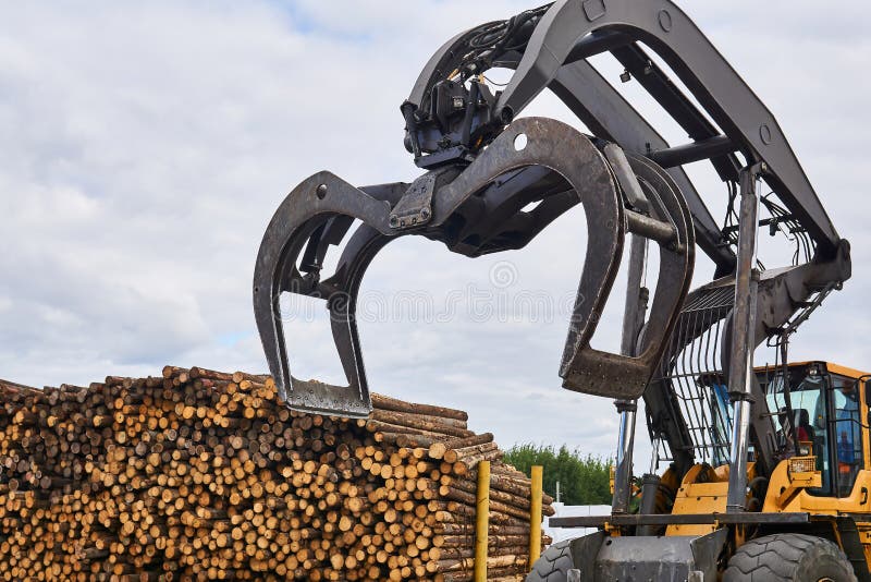 Bucket a forestry grapple loader against the background of a stack of logs outdoors stock photography