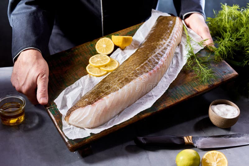 Bucătar nerecunoscut cu filet de pește crud în bucătărie stock photography