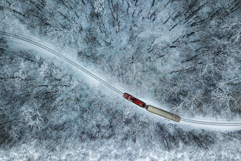 Budapest, Hungary - Aerial view of snowy forest with red train on a track at winter time