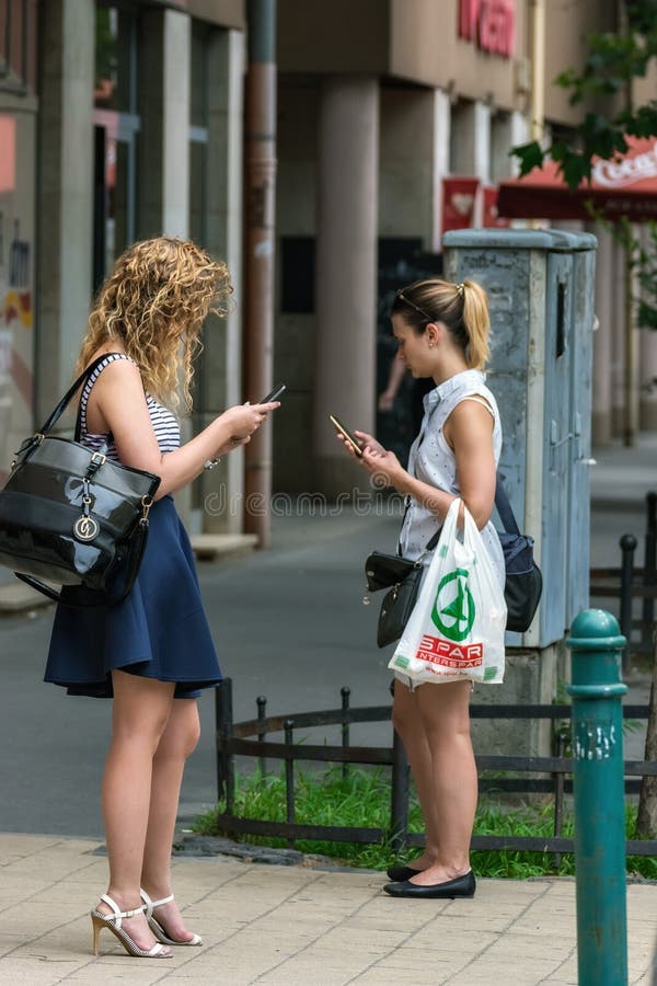 Budapest, Hungary, July 04: Two unfamiliar girls stand and look at their ph...