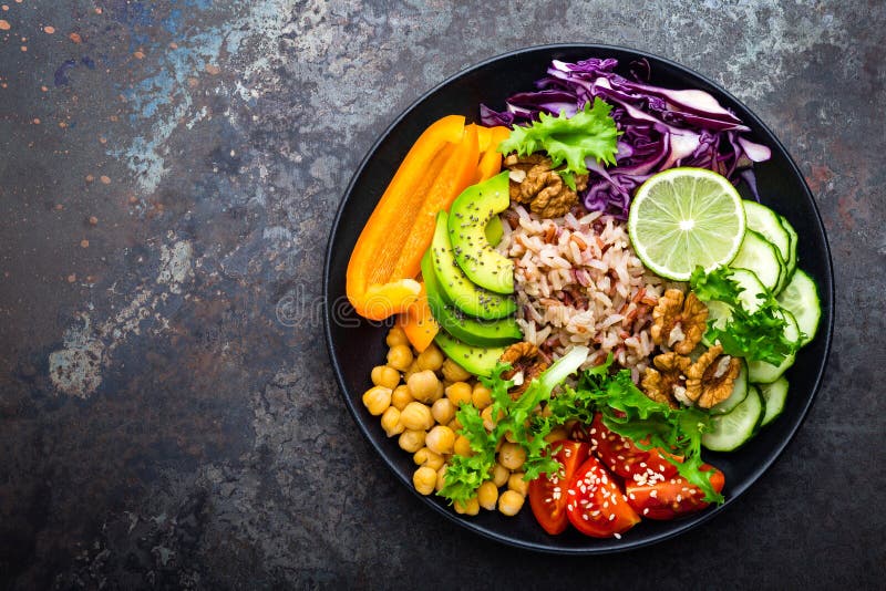 Buddha bowl dish with brown rice, avocado, pepper, tomato, cucumber, red cabbage, chickpea, fresh lettuce salad and walnuts. Healt