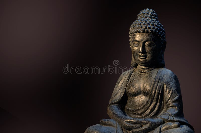 Buddha Statue Sitting in Meditation Pose Against Deep Dark Background