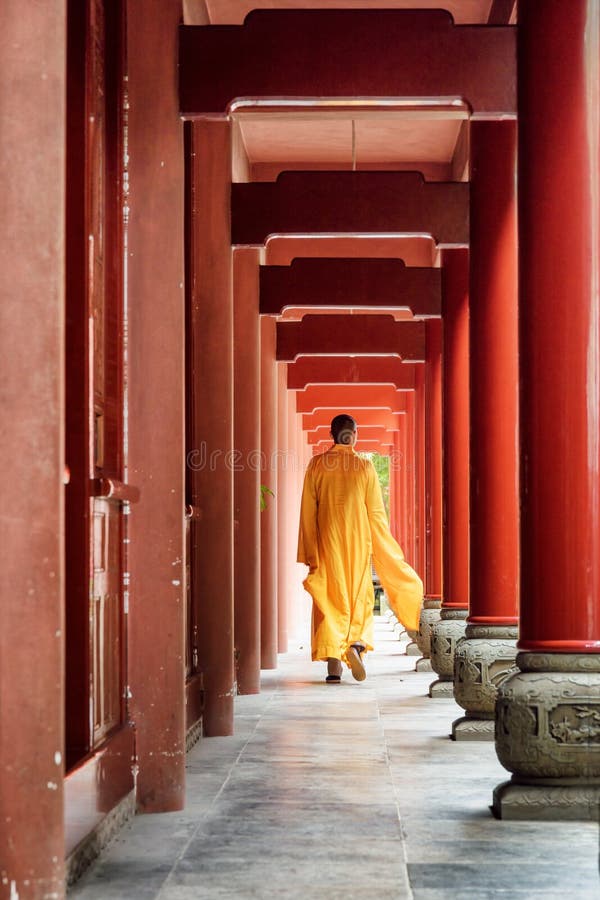 Buddhist monk walking along red wooden corridor of a monastery