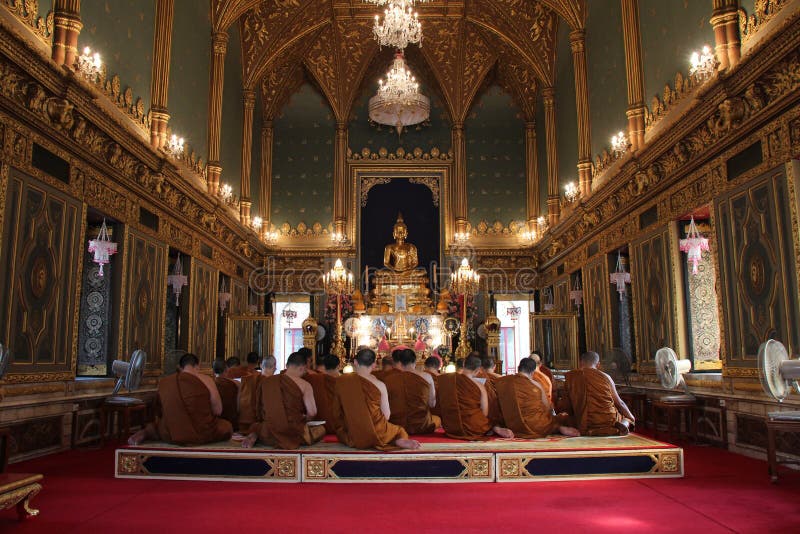 Buddhist monks are praying in the main hall of the Wat Ratchabophit, in Bangkok (Thailand)