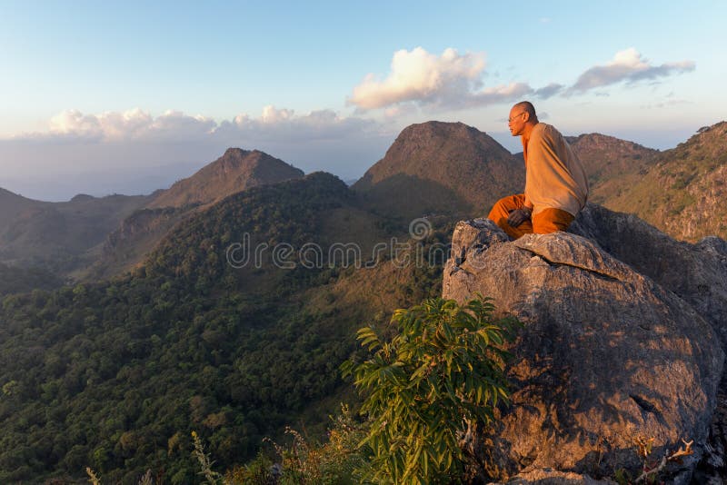 CHIANG DAO, THAILAND, JANUARY 05, 2015: A Buddhist monk master is meditating at the top of the Chiang Dao mount at dusk for the new year in Thailand. CHIANG DAO, THAILAND, JANUARY 05, 2015: A Buddhist monk master is meditating at the top of the Chiang Dao mount at dusk for the new year in Thailand.