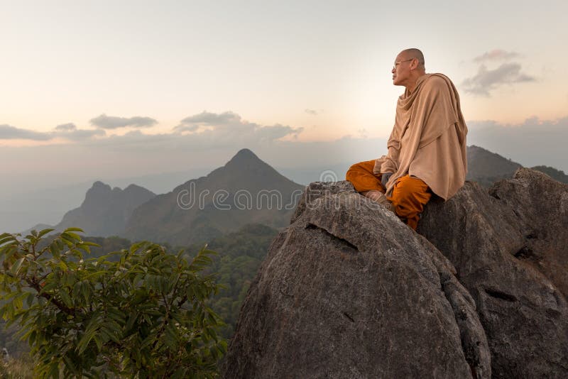 CHIANG DAO, THAILAND, JANUARY 05, 2015: A Buddhist monk master is meditating at the top of the Chiang Dao mount at dusk for the new year in Thailand. CHIANG DAO, THAILAND, JANUARY 05, 2015: A Buddhist monk master is meditating at the top of the Chiang Dao mount at dusk for the new year in Thailand.