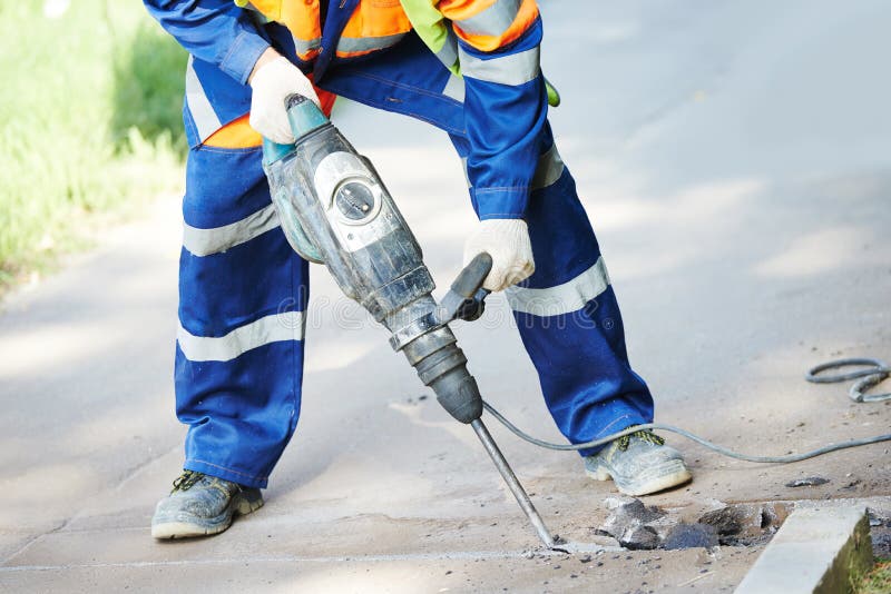 Builder worker with pneumatic hammer drill equipment breaking asphalt at road construction site. Builder worker with pneumatic hammer drill equipment breaking asphalt at road construction site