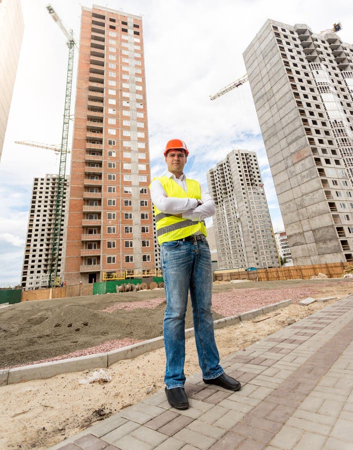 Budowa inżyniera pozycja przed budynkami pod const zdjęcie stock