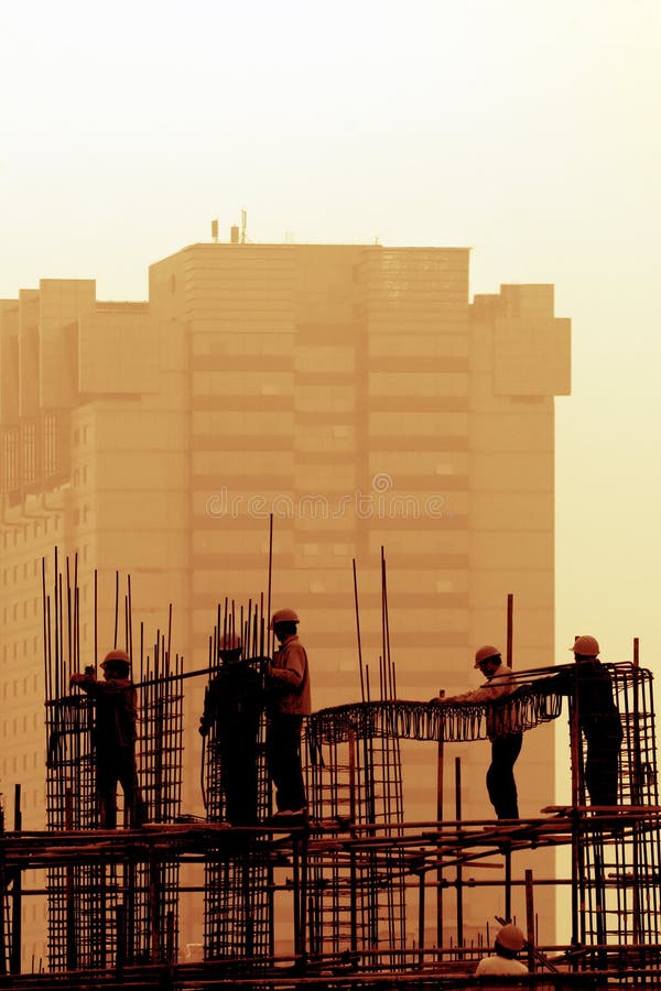 Worker on roof and crane on construction site silhouetted against orange sunset. Picture color is dealt with by PHOTSHOP. Worker on roof and crane on construction site silhouetted against orange sunset. Picture color is dealt with by PHOTSHOP