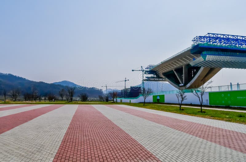 Sejong, South Korea; April 1, 2020: Side perspective view of new bridge under construction through wilderness public park. Sejong, South Korea; April 1, 2020: Side perspective view of new bridge under construction through wilderness public park