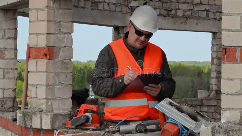 Budowniczy sprawdza i pisze w niedokończonym budynku