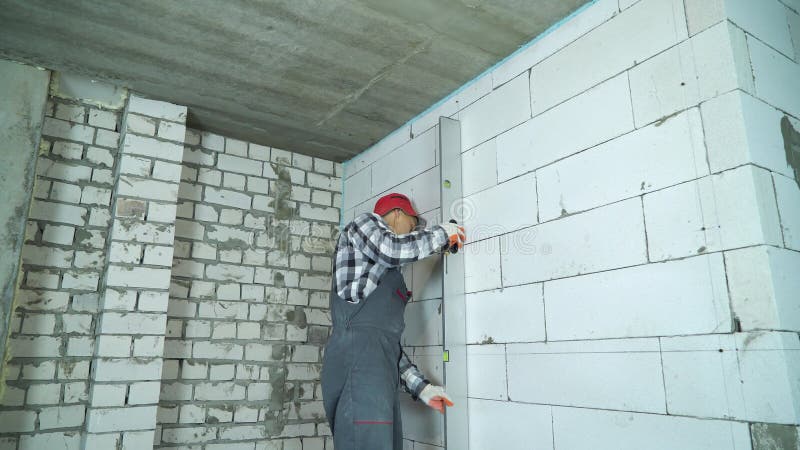 Budowniczy sprawdza ocechowania na wietrzącej betonowy blok ścianie z budowy władcą