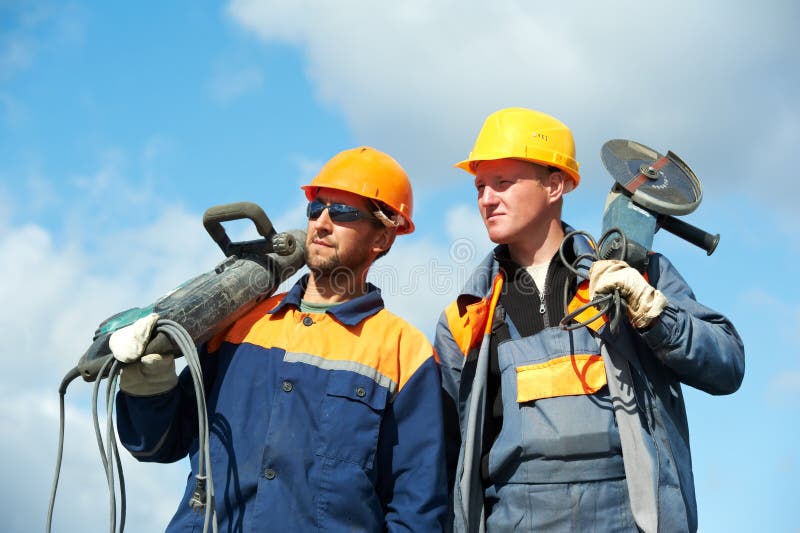 Two Builder workers with pneumatic hammer and grinding machine equipment over blue sky. Two Builder workers with pneumatic hammer and grinding machine equipment over blue sky