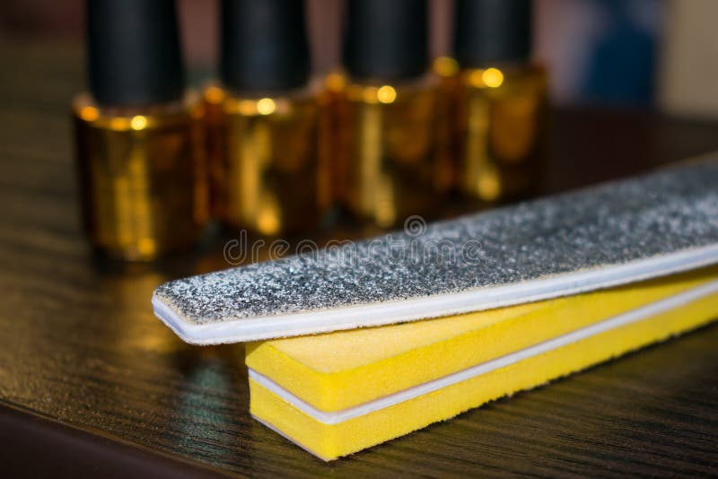 Buff and nail file on the background of bottles of nail polish. royalty free stock photography Buff and nail file on the background of bottles of nail polish. royalty free stock photography