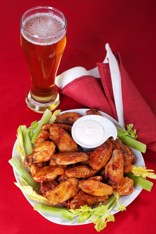 Pouring Beer with Chicken Wings in Background. Stock Photo Image of
