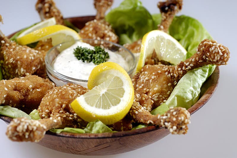 serving bowl of sesame buffalo wings (which are chicken wings) with a ranch dip and lemon garnish. serving bowl of sesame buffalo wings (which are chicken wings) with a ranch dip and lemon garnish