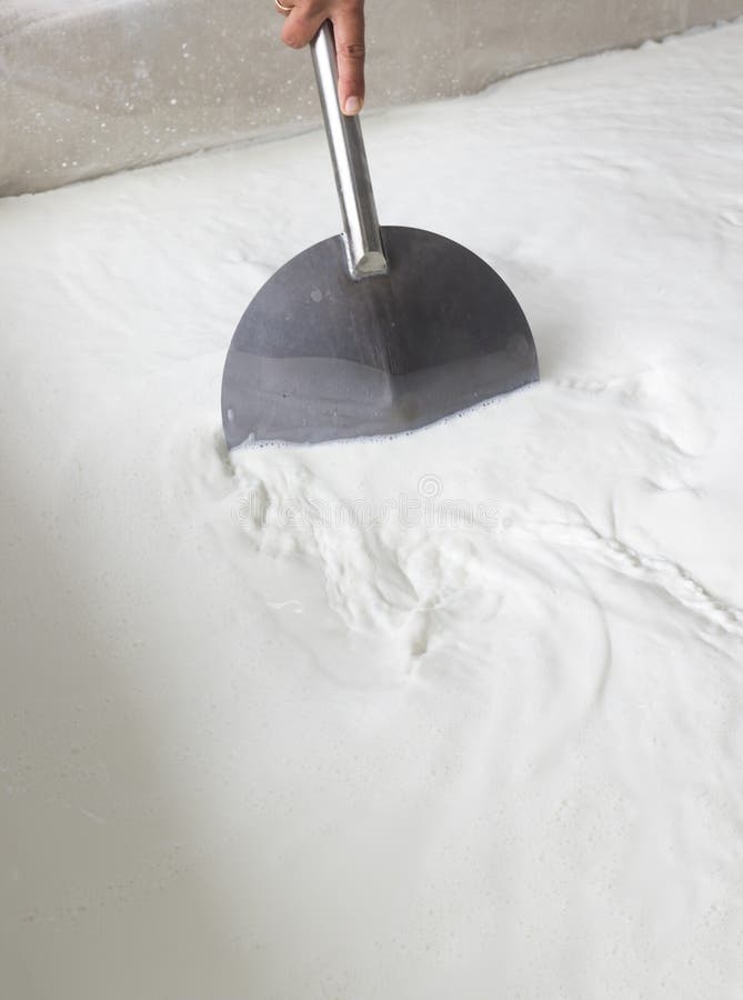 A woman working in a small family creamery is mixing a cheese batch. The dairy farm is specialized in buffalo yoghurt and cheese production. A woman working in a small family creamery is mixing a cheese batch. The dairy farm is specialized in buffalo yoghurt and cheese production.