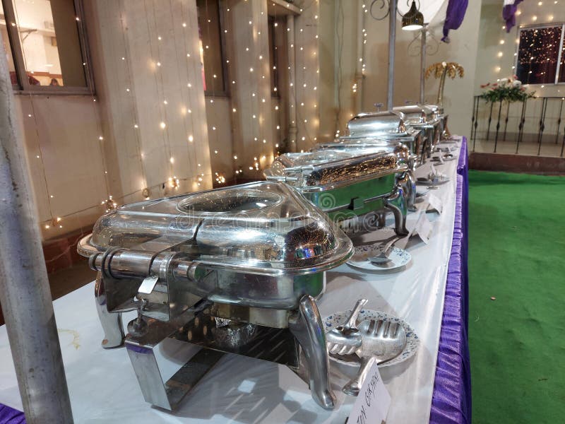 A Buffet Lunch Table ,with Electrical Oven ,tray and Serving Spoons Along with Light Decorations