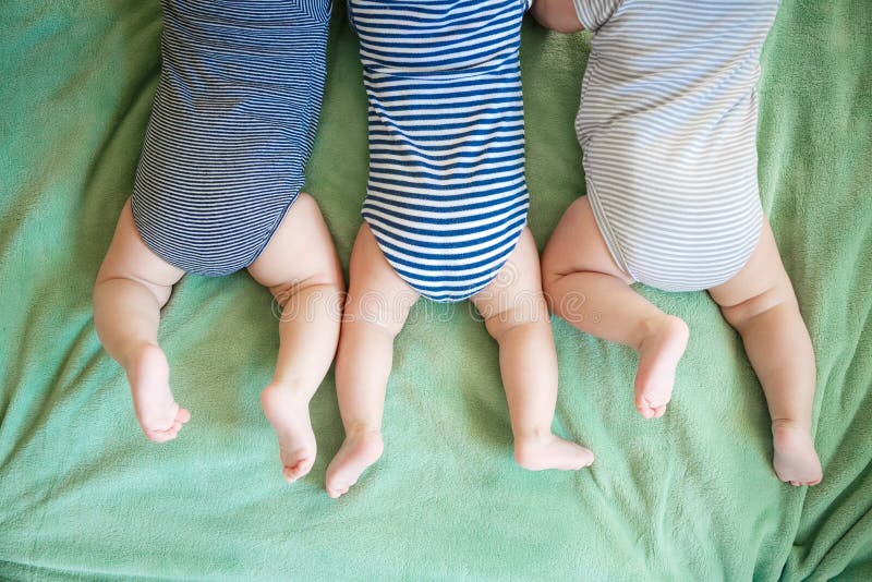 Newborn triplets lie on a stomach on a blanket. Newborn triplets lie on a stomach on a blanket