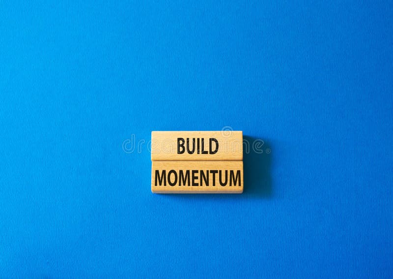 Build momentum symbol. Wooden blocks with words Build momentum. Beautiful blue background. Business and Build momentum concept. stock images