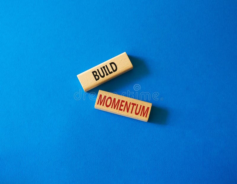 Build momentum symbol. Wooden blocks with words Build momentum. Beautiful blue background. Business and Build momentum concept. stock images