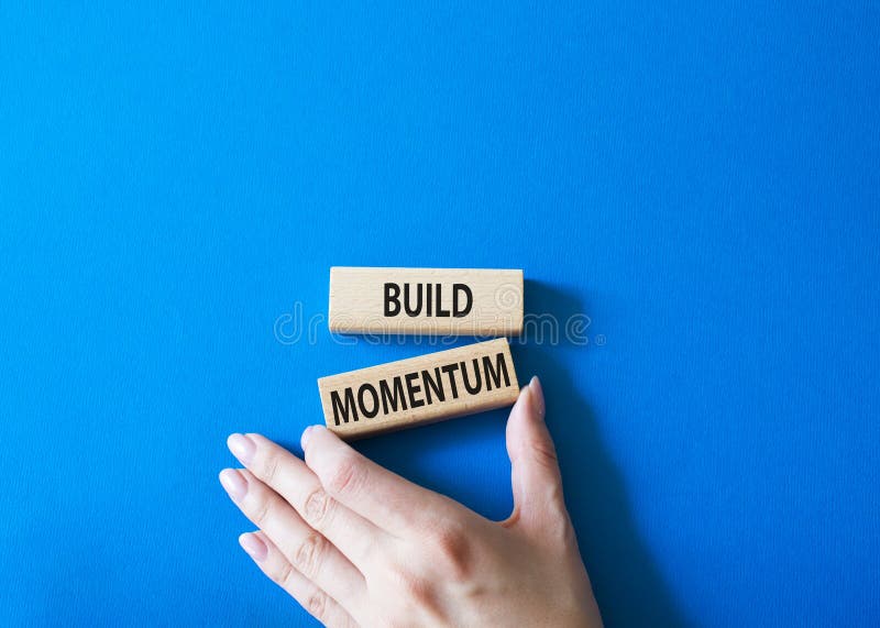 Build momentum symbol. Wooden blocks with words Build momentum. Beautiful blue background. Businessman hand. Business and Build royalty free stock photos