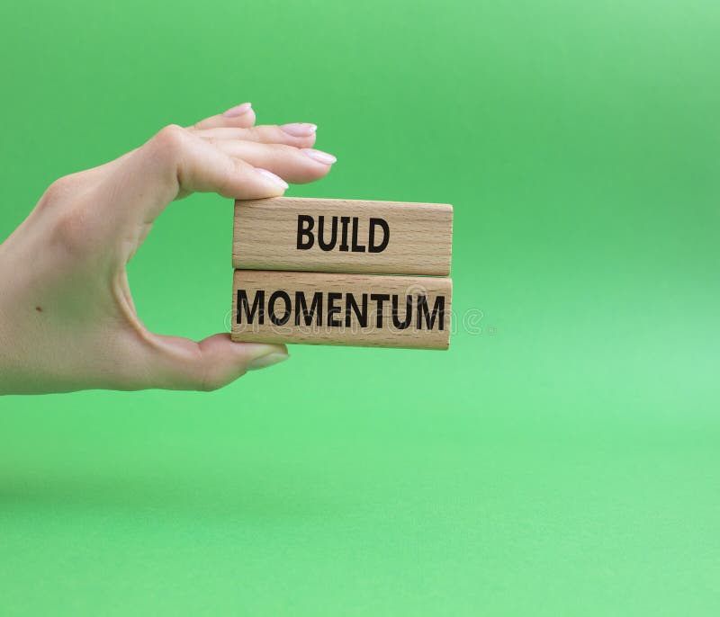 Build momentum symbol. Wooden blocks with words Build momentum. Beautiful green background. Businessman hand. Business and Build stock photography