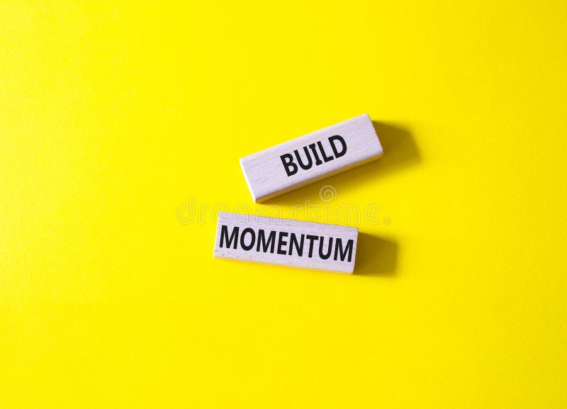 Build momentum symbol. Wooden blocks with words Build momentum. Beautiful yellow background. Business and Build momentum concept. stock photos