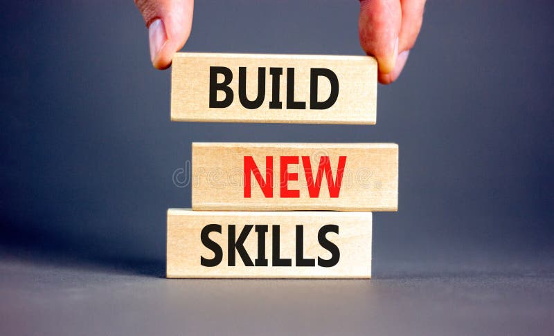 Build new skills symbol. Concept word Build new skills on beautiful wooden block. Businessman hand. Beautiful grey table grey stock photo
