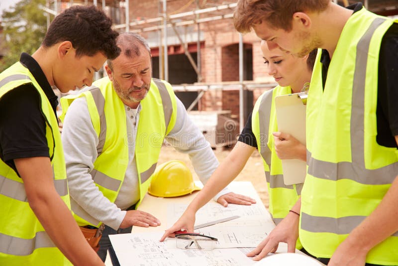Builder On Building Site Discussing Work With Apprentice stock photos