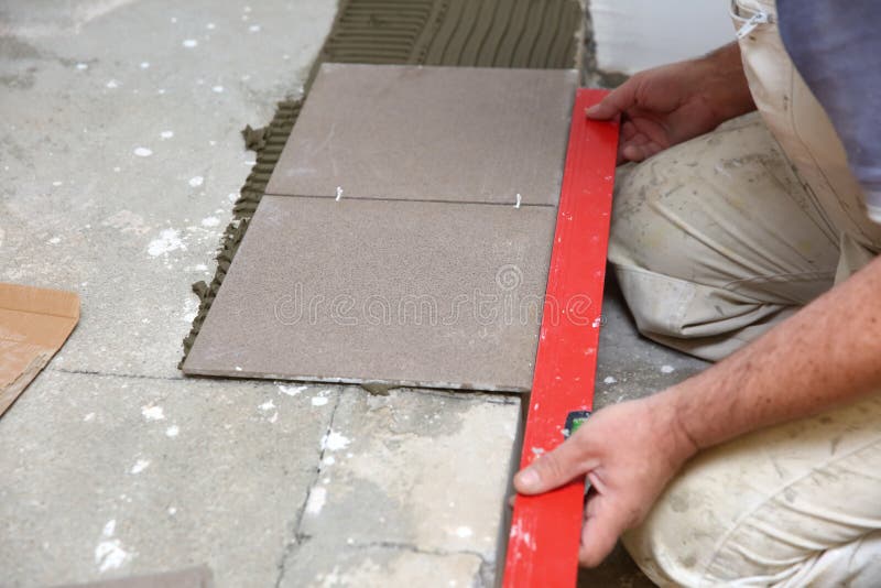 Free Photo  Builder checks the quality of the laid tiles with a manual  bubble level construction worker installing ceramic floor tiles on  construction sites floor repair selective focus