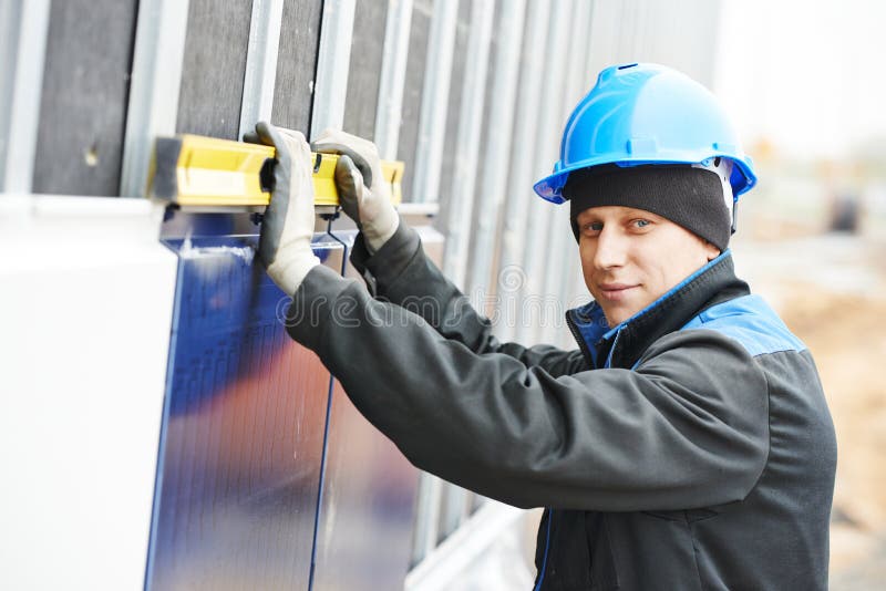 Plasterer builder worker with level examining metal profile facade plate installation. Plasterer builder worker with level examining metal profile facade plate installation