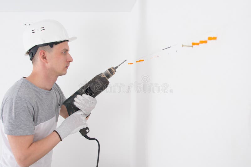 Builder with a Hammer Drill, Makes a Hole in the Wall for Fixing
