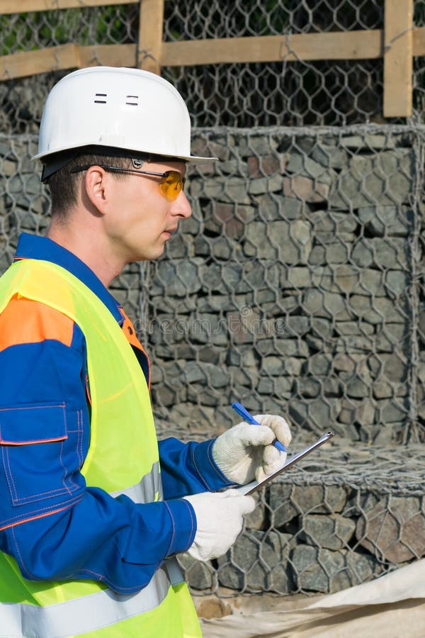 A builder in a helmet records violations in the protocol during the commissioning of the object stock photos A builder in a helmet records violations in the protocol during the commissioning of the object stock photos