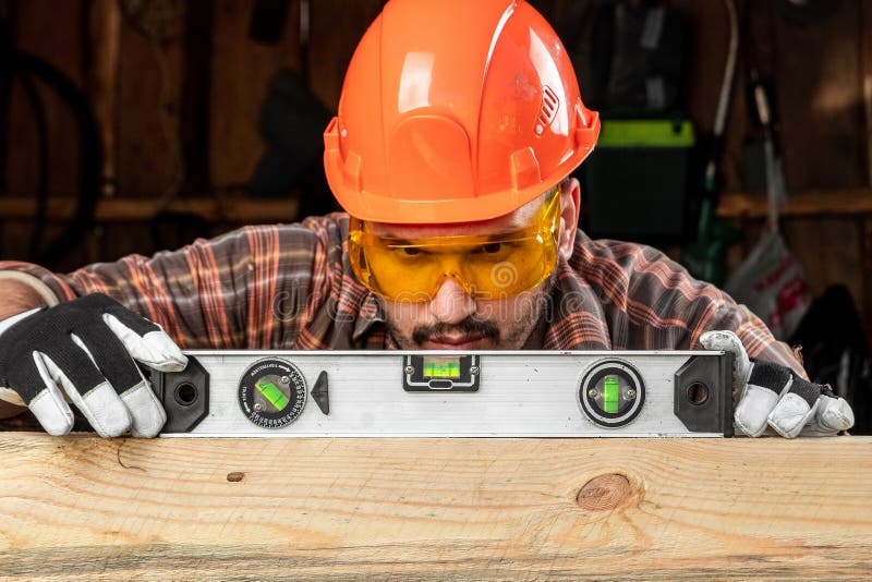 Builder man looks at the construction level checks the horizontal surface, male hands with a level close-up. Construction work royalty free stock photos