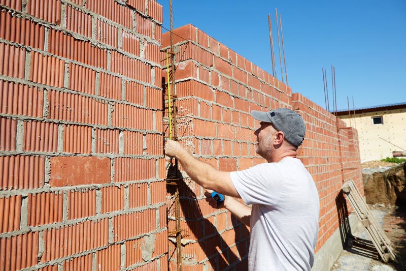 A construction worker is measuring a brick wall at a building site royalty free stock photo