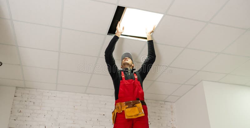 A builder replacing ceiling panel, working, armstrong. stock photography