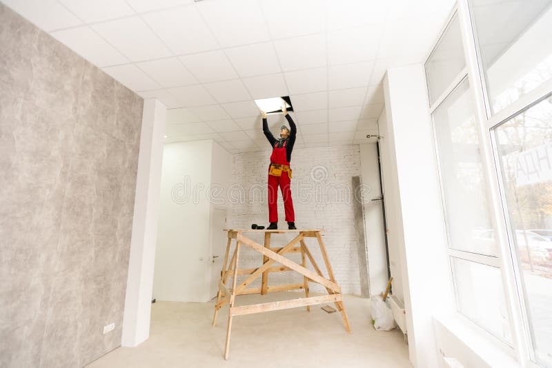 Builder replacing ceiling panel, working, ceiling armstrong royalty free stock photos