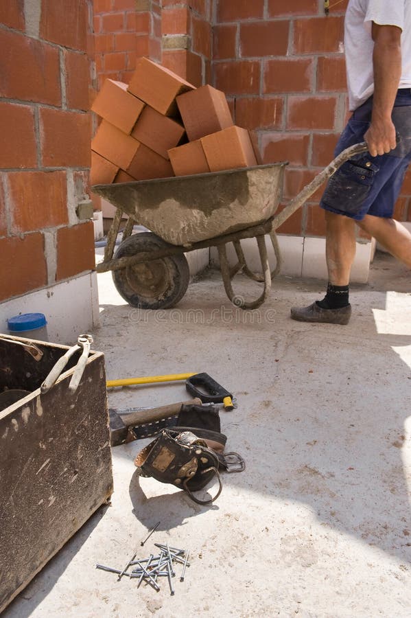 Builders carrying a wheelbarrow Under construction