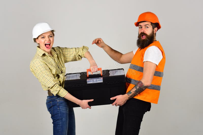 Builders with toolbox, couple in love makes repair grey background. Renovation concept. Smiling woman in helmet excited