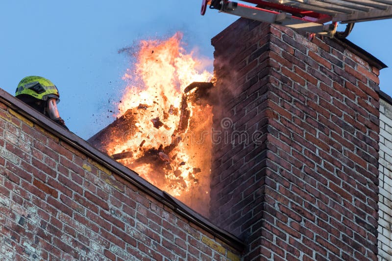 Building on fire with flame around chimney.